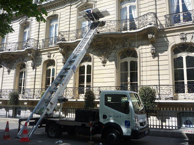 Monte-meuble télescopique installé devant un immeuble haussmannien à Paris